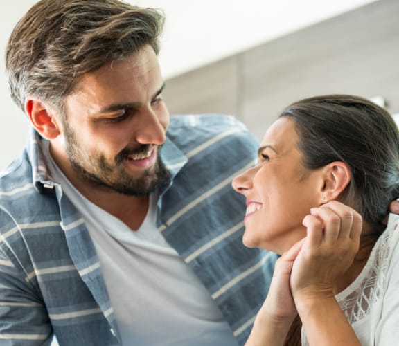 Couple sitting in their kitchen looking at each other and smiling