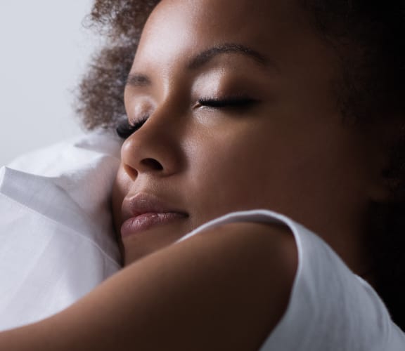 Woman laying down hugging pillow and sleeping on it